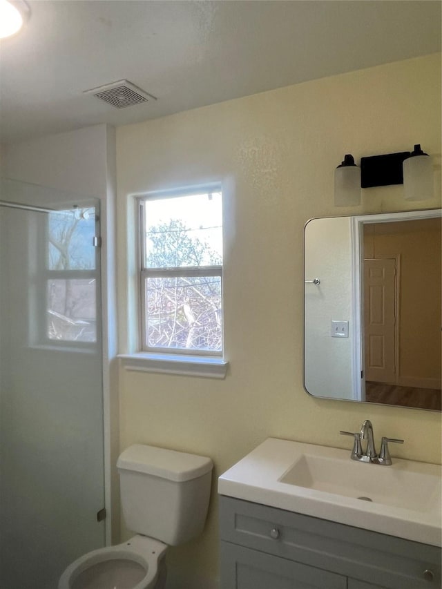 full bath with vanity, toilet, visible vents, and walk in shower