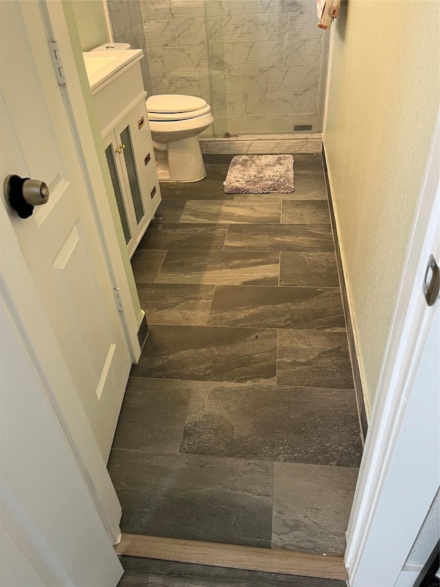 bathroom with a shower stall, baseboards, toilet, wood finished floors, and vanity