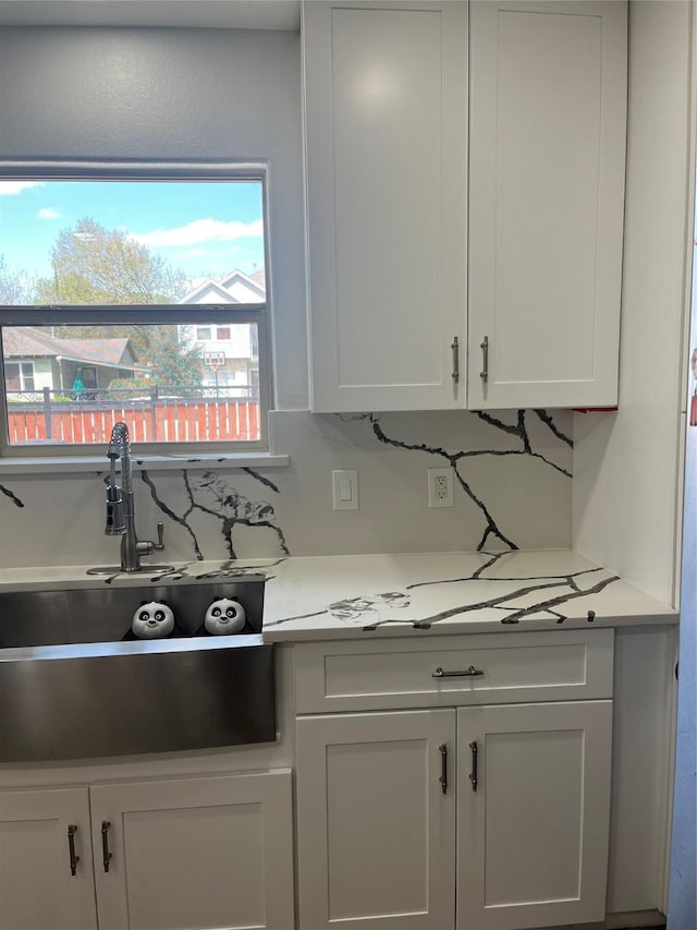 kitchen with decorative backsplash, white cabinets, light countertops, and a sink