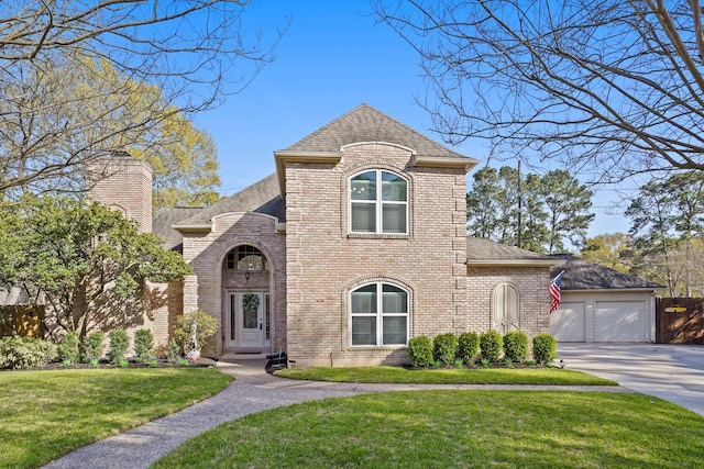 french country style house with a front lawn, brick siding, roof with shingles, and a chimney