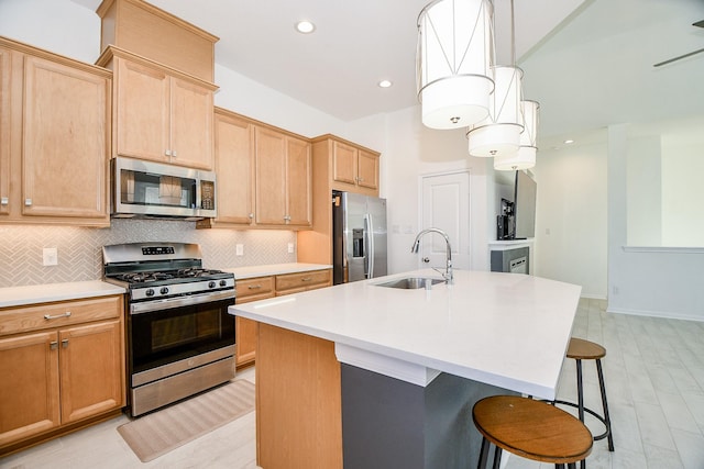 kitchen featuring a breakfast bar, a sink, stainless steel appliances, light countertops, and tasteful backsplash