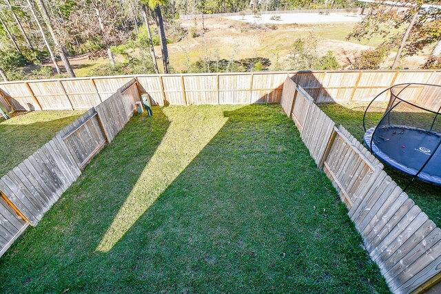 view of yard featuring a fenced backyard and a trampoline