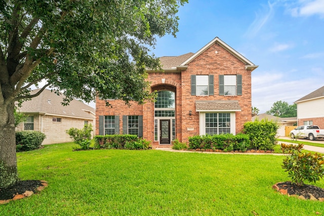 traditional-style house featuring a front lawn, brick siding, and a shingled roof