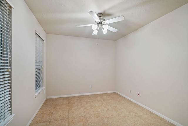 empty room with a textured ceiling, a ceiling fan, and baseboards