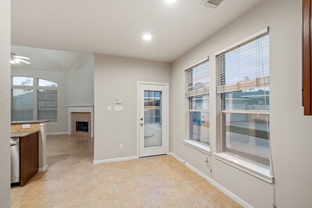 interior space with visible vents, ceiling fan, baseboards, light tile patterned floors, and a tile fireplace