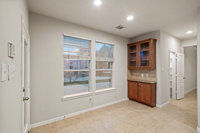 kitchen with visible vents, glass insert cabinets, decorative backsplash, recessed lighting, and brown cabinetry