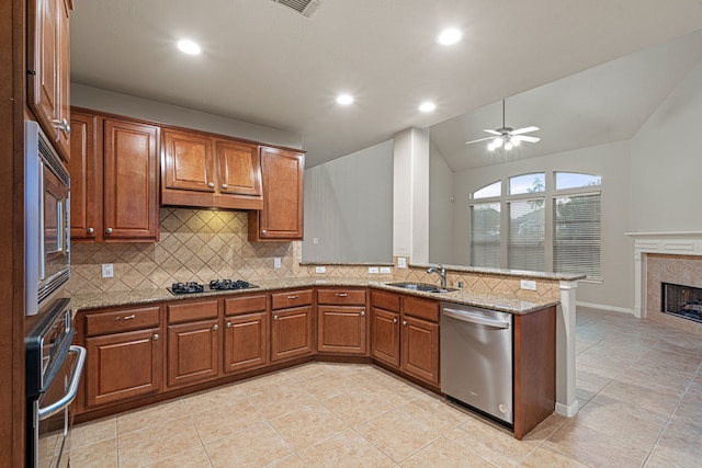 kitchen with a tiled fireplace, a peninsula, brown cabinetry, stainless steel appliances, and a sink