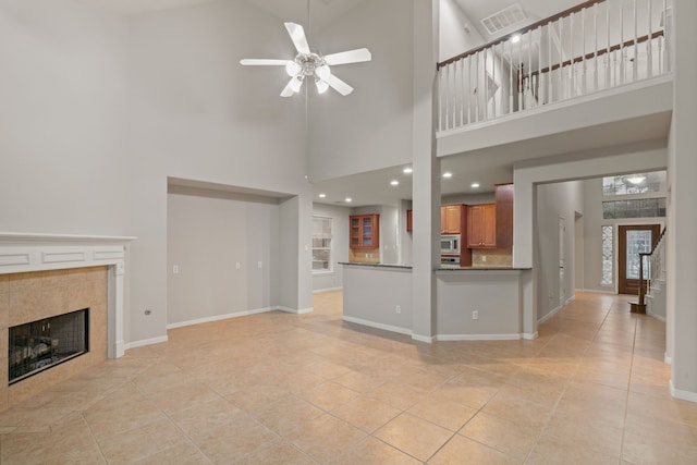 unfurnished living room with baseboards, a fireplace, visible vents, and ceiling fan