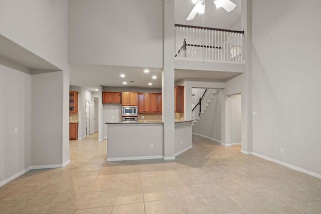 kitchen with a ceiling fan, baseboards, decorative backsplash, appliances with stainless steel finishes, and brown cabinets