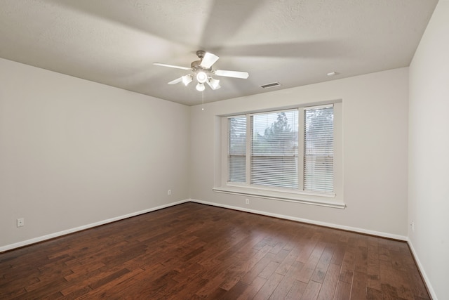 unfurnished room featuring visible vents, a textured ceiling, dark wood-style floors, baseboards, and ceiling fan