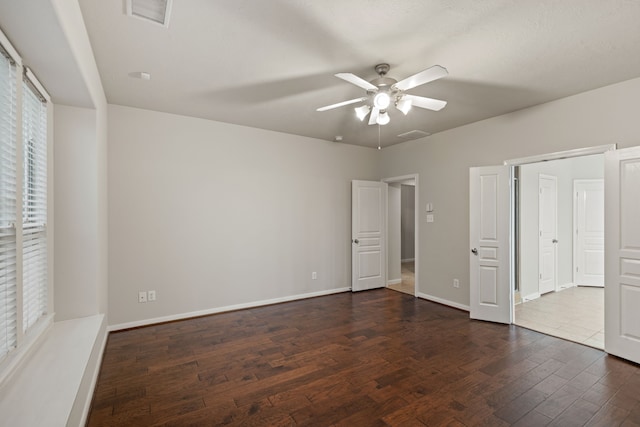 unfurnished bedroom featuring dark wood finished floors, baseboards, visible vents, and a ceiling fan