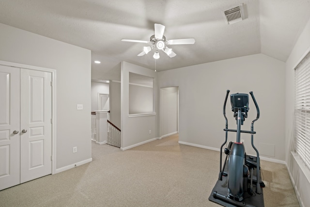 workout room with visible vents, a ceiling fan, carpet floors, baseboards, and vaulted ceiling