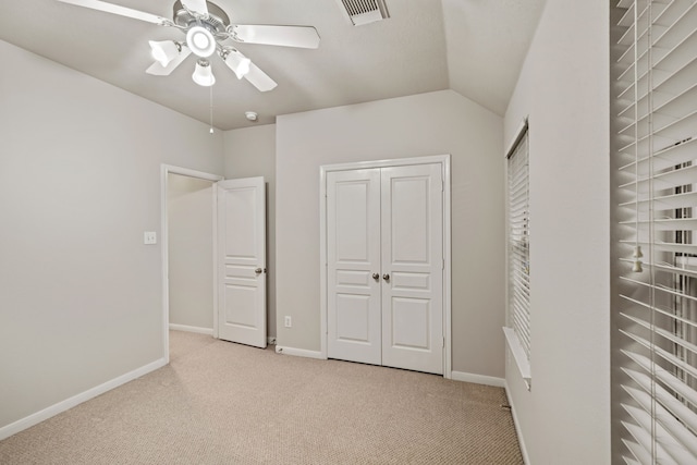 unfurnished bedroom featuring visible vents, baseboards, carpet, and vaulted ceiling