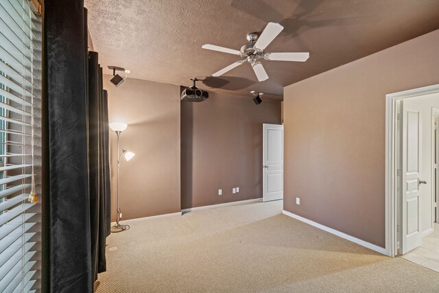 unfurnished bedroom with a textured ceiling, connected bathroom, carpet, baseboards, and ceiling fan