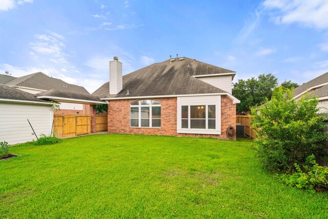 rear view of house with a lawn, brick siding, a fenced backyard, and a chimney