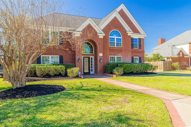 traditional-style house with brick siding, a front yard, and fence