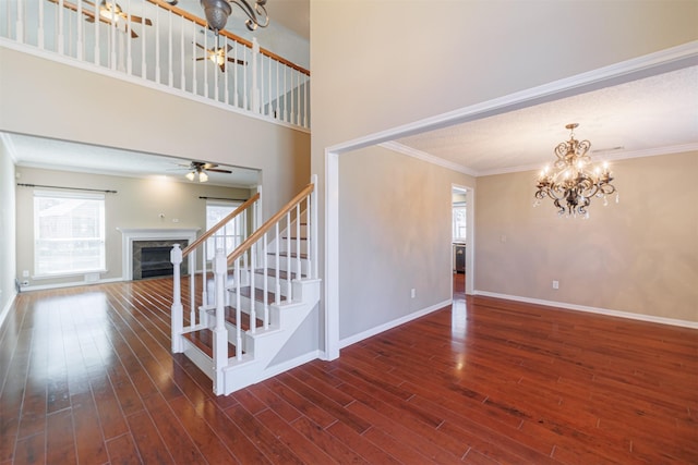 foyer entrance with wood finished floors, a high end fireplace, crown molding, baseboards, and stairs