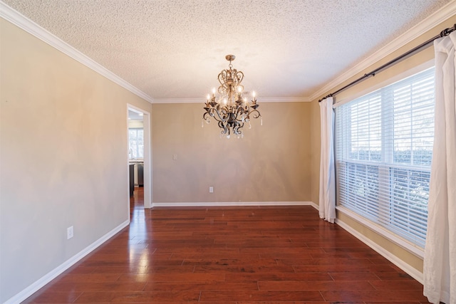 spare room with a chandelier, a textured ceiling, wood finished floors, and crown molding