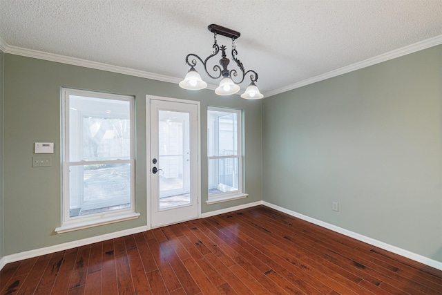 spare room featuring baseboards, dark wood-style flooring, a textured ceiling, crown molding, and a notable chandelier