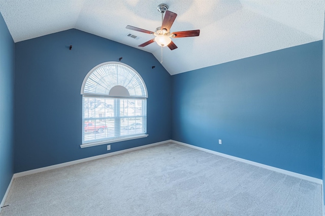 carpeted spare room with visible vents, a textured ceiling, baseboards, lofted ceiling, and ceiling fan