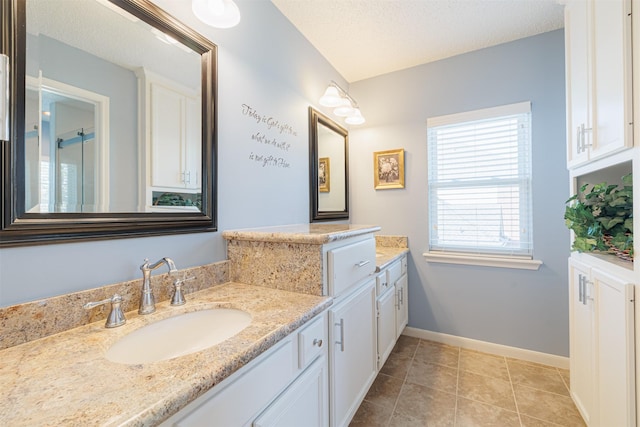 bathroom featuring tile patterned floors, a textured ceiling, vanity, and baseboards