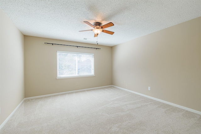 unfurnished room featuring baseboards, light colored carpet, a textured ceiling, and a ceiling fan