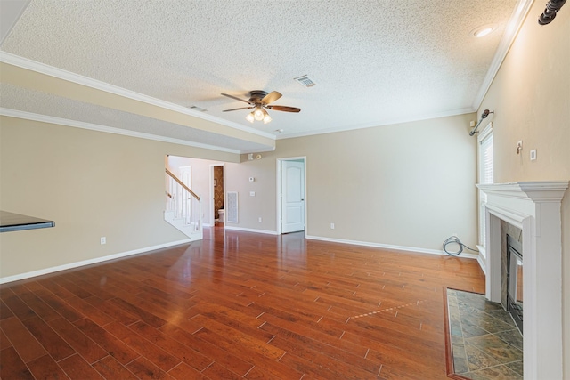 unfurnished living room featuring a tiled fireplace, stairway, wood finished floors, and a textured ceiling