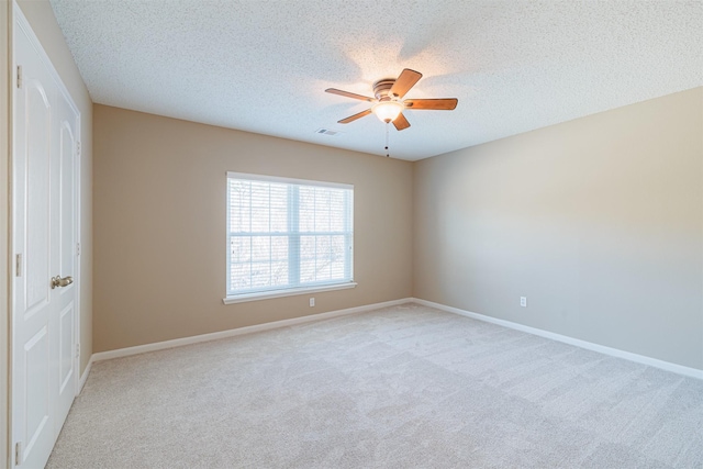 unfurnished room featuring visible vents, baseboards, ceiling fan, light carpet, and a textured ceiling