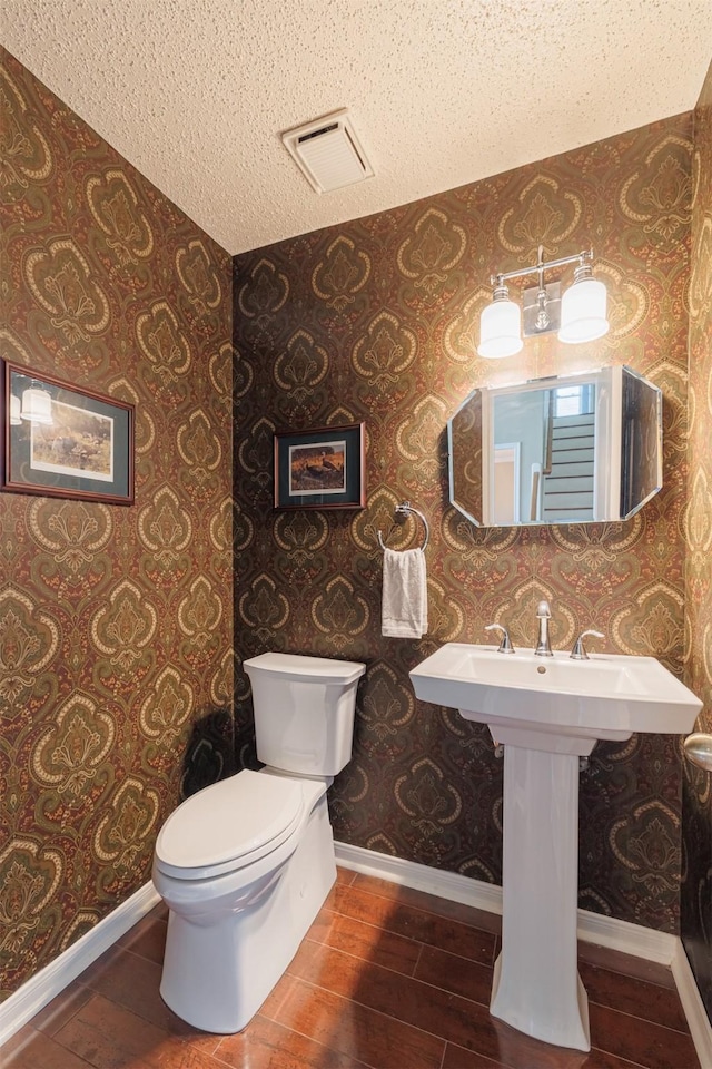 bathroom featuring wallpapered walls, wood finished floors, and visible vents