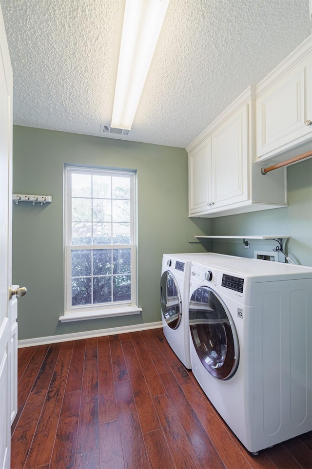 clothes washing area with washer and dryer, dark wood-style floors, cabinet space, and baseboards