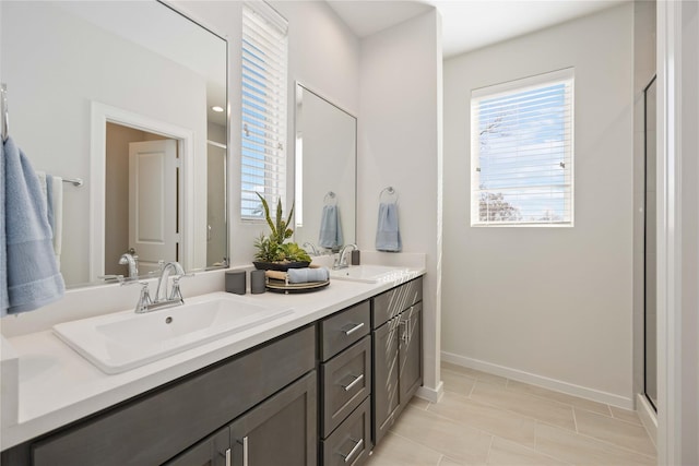 bathroom with double vanity, baseboards, a shower stall, and a sink