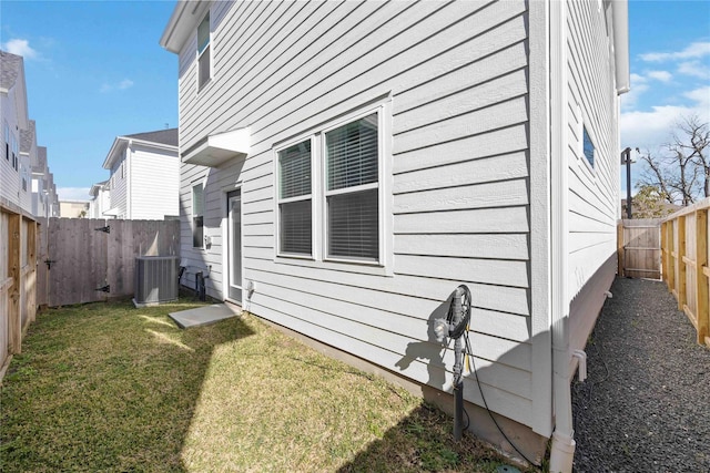 view of side of property with a fenced backyard, central air condition unit, and a yard