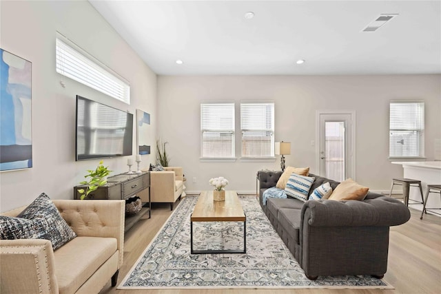 living area with recessed lighting, visible vents, a healthy amount of sunlight, and wood finished floors