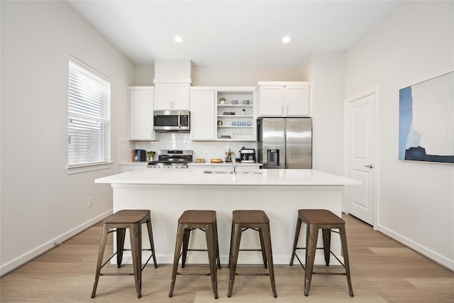 kitchen featuring a sink, backsplash, white cabinets, stainless steel appliances, and open shelves