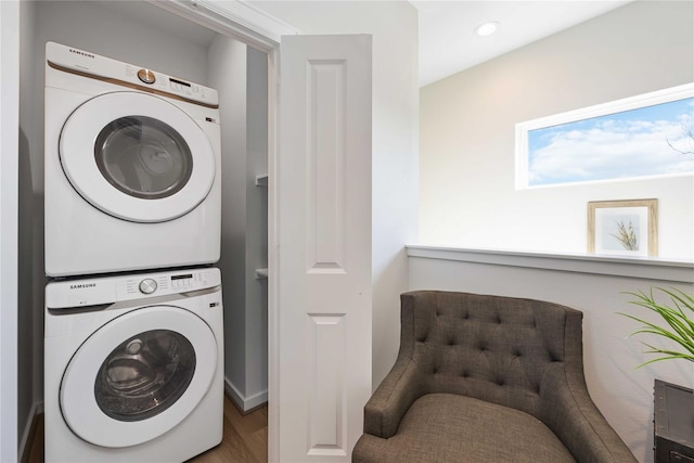 laundry area with laundry area, recessed lighting, stacked washer and clothes dryer, and wood finished floors