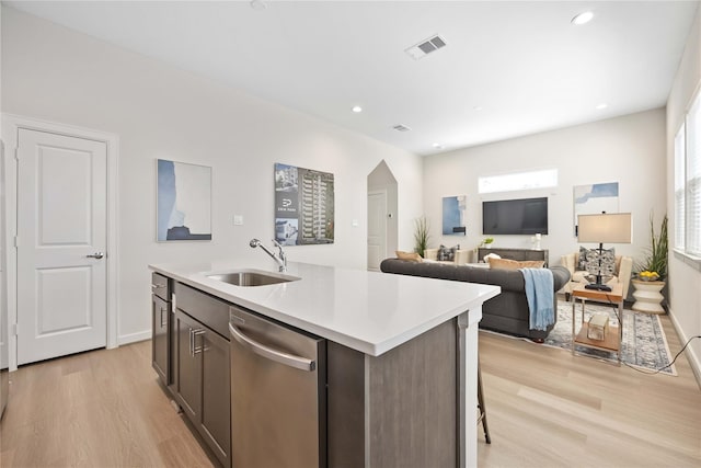 kitchen featuring visible vents, dishwasher, an island with sink, light wood-style flooring, and a sink