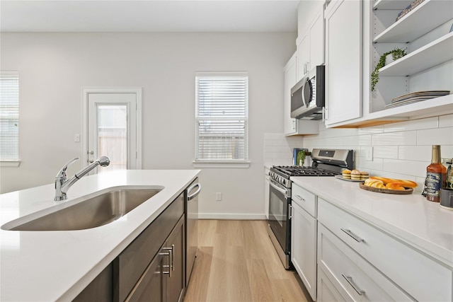 kitchen featuring backsplash, stainless steel appliances, light countertops, and a sink