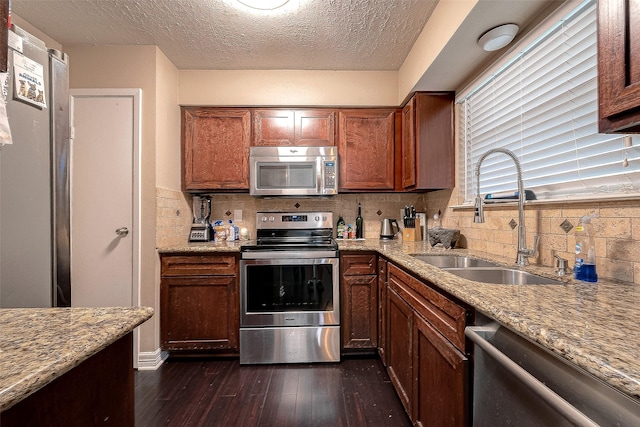 kitchen featuring dark wood-style floors, a sink, stainless steel appliances, a textured ceiling, and tasteful backsplash