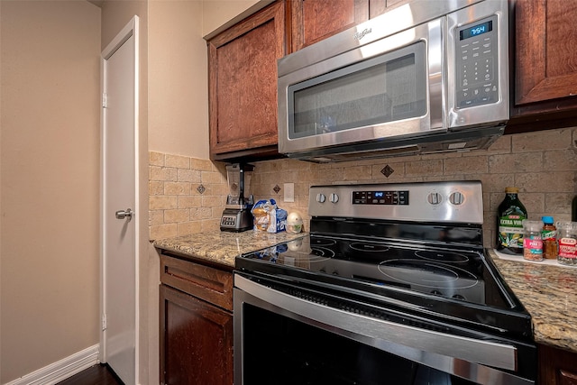 kitchen with brown cabinetry, baseboards, tasteful backsplash, and stainless steel appliances