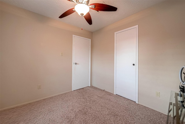 unfurnished bedroom with baseboards, carpet, a ceiling fan, and a textured ceiling