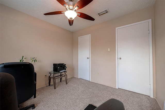 carpeted office space with a ceiling fan, visible vents, and a textured ceiling