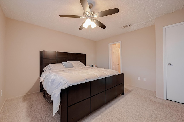 bedroom with visible vents, light colored carpet, and a textured ceiling