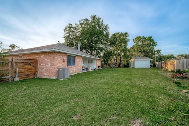 view of yard featuring an outbuilding, central air condition unit, a storage unit, and a fenced backyard