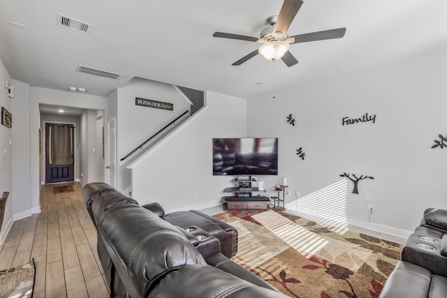 living area featuring stairway, baseboards, visible vents, and light wood-type flooring