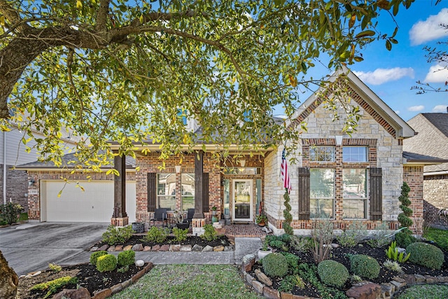 view of front of property featuring concrete driveway, brick siding, a garage, and stone siding