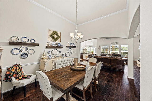 dining area featuring dark wood finished floors, ceiling fan with notable chandelier, arched walkways, and ornamental molding