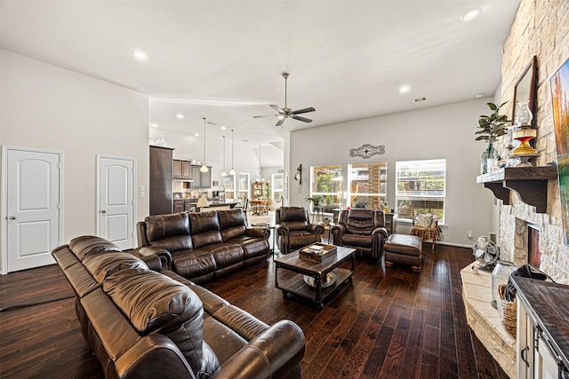 living room with high vaulted ceiling, a ceiling fan, hardwood / wood-style floors, recessed lighting, and a stone fireplace