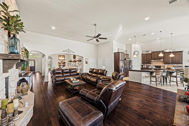 living room with visible vents, hardwood / wood-style flooring, arched walkways, a fireplace, and ceiling fan