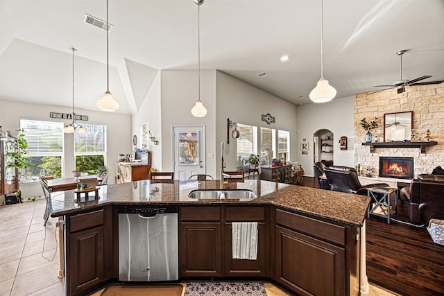 kitchen featuring visible vents, a sink, a stone fireplace, ceiling fan, and dishwasher