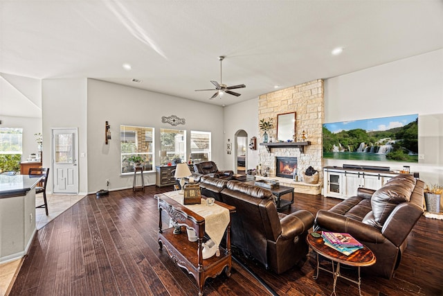 living room featuring visible vents, a ceiling fan, dark wood finished floors, arched walkways, and a fireplace